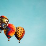 3 colorful hot air balloons floating against a blue background
