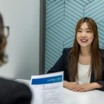 A woman in business attire is being interviewed by a person holding a resume.